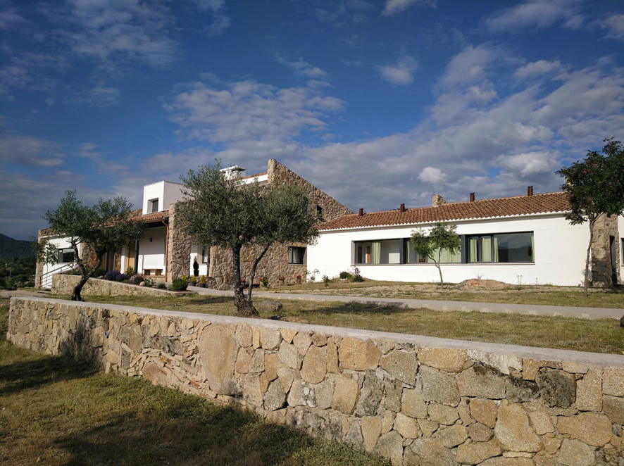 Edificio del Monasterio de la Conversión con muros de piedra y olivos