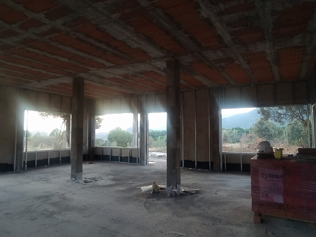 Interior en obras con grandes ventanales abiertos hacia la sierra
